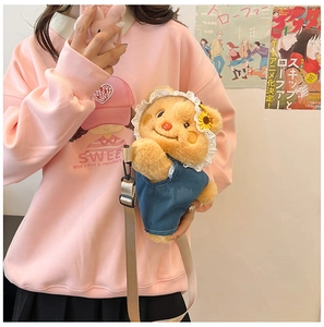 Detail of cute brown plush bear bag with lace sunflower headpiece and blue overalls