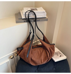 Close-up of caramel suede hobo bag with adjustable black leather strap and silver buckle