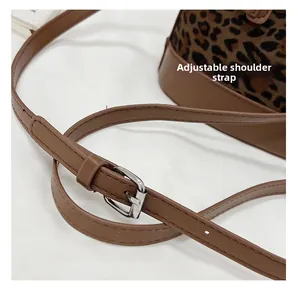 Detail view of the adjustable leopard print bucket bag strap with a metal buckle