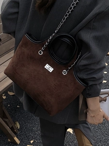Brown quilted suede tote bag with black leather trim and chain strap on grey blazer outfit