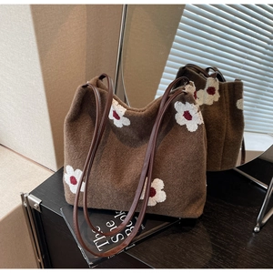 Detail showing plush brown tote bag texture with white flower embroidery and leather strap