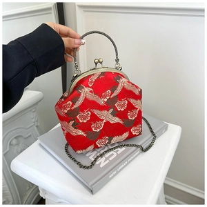 Close-up of red brocade bag with crane embroidery and antique bronze handle