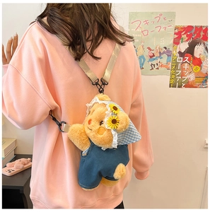 Detail of yellow plush bear crossbody bag wearing blue overalls and sunflower headscarf