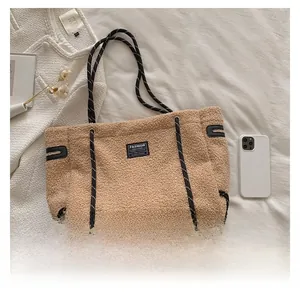 Détail d'un sac cabas beige en polaire avec poignées en corde noire et écusson brodé