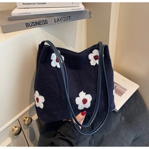 Detail of navy knit tote bag featuring white floral patterns and synthetic leather straps