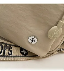 Gros plan sur la texture du nylon beige avec logo métallique et sangle jacquard