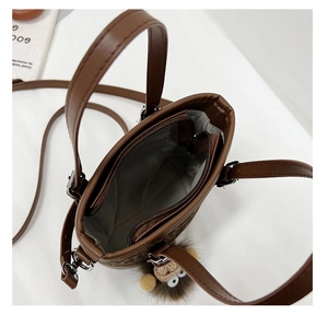 Top view showing the zipper closure and gray interior of the brown leather bucket bag