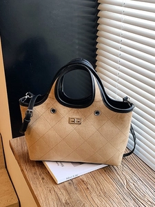 Retro beige quilted tote bag with black trim and gold twist-lock on a wooden table