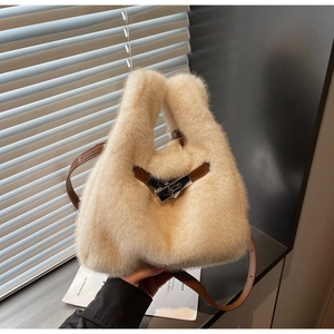Dettaglio della borsa in ecopelliccia color crema con manico in pelle marrone e chiusura argento