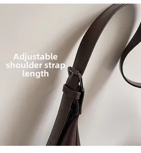 Detail of adjustable leather shoulder strap with gunmetal buckle on dark brown handbag