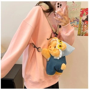 Detail of cute teddy bear plush backpack wearing blue denim overalls and sunflower hat
