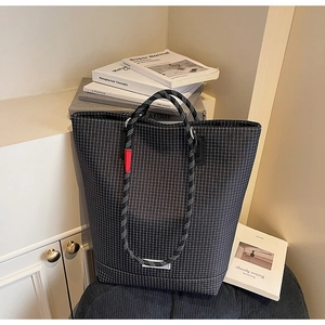 Detail of black and white checkered tote bag with thick rope handles and red accents
