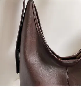 Detail view of reinforced stitching and textured dark brown leather on a shoulder bag