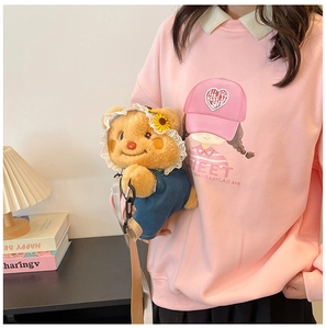 Detail shot of a cute plush bear backpack worn with a pink girl's cartoon sweatshirt