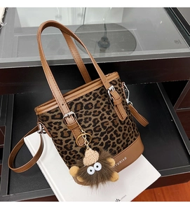 Close-up of leopard print bucket bag with leather trim and plush monster charm