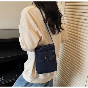 Detail view of dark blue denim mini crossbody bag with silver button front flap pocket