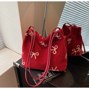 Detail of red wool felt tote bag with white bow pattern and leather straps