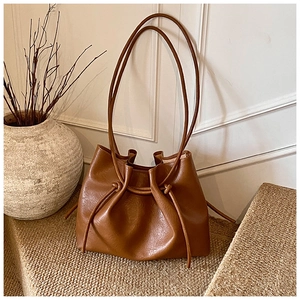 Detailansicht der braunen Retro-Achseltasche mit Tunnelzug-Knoten auf weichem Teppich