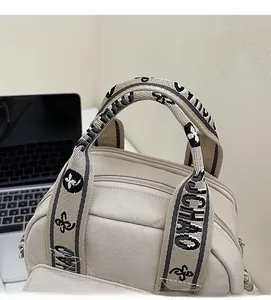 Détail du sac à main en nylon beige avec sangles tissées griffées et fermeture éclair en métal