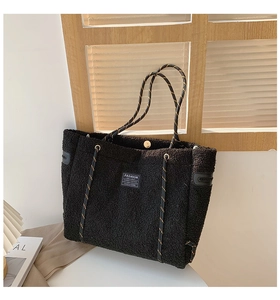 Détail d'un sac cabas noir en polaire avec anses tissées bleues et patch logo