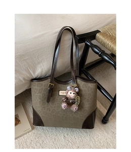 Dettaglio della borsa tote leopardata con manici in pelle e portachiavi a orsetto