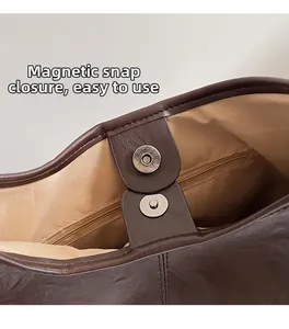 Detail view of magnetic snap closure and internal zipper pocket on dark brown tote bag