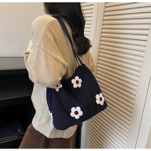 Detail of navy knit tote bag with white 3D flowers on model with oatmeal sweater