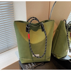 Detail showing green checkered tote bag fabric texture and woven rope handle