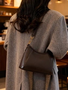 Vintage dark brown leather hobo bag with bohemian woven strap on a grey coat