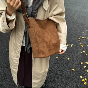 Detail of vintage brown suede tote with woven shoulder strap and silver metal buckle