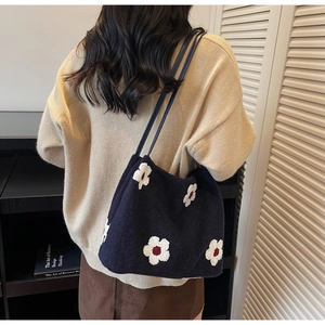Detail of knit shoulder bag with floral embroidery on soft black fabric for winter