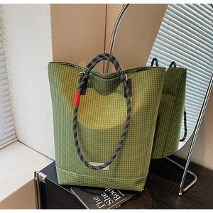 Detailed view of green checkered canvas tote bag with woven rope handles and brand tag