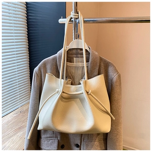 Detailaufnahme des Knotenträgers und der gefalteten Lederstruktur einer cremeweißen Tasche