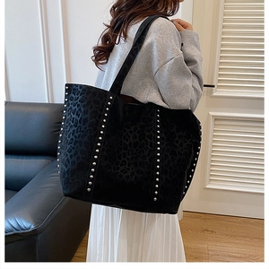 Detail of leopard print tote bag with silver metal studs shown on a model's shoulder