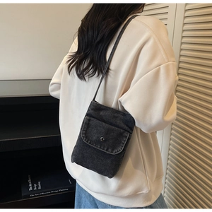 Close-up of a dark denim crossbody phone bag with snap button and slim strap