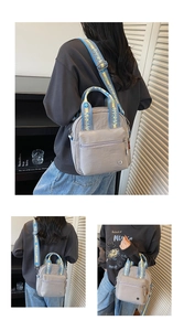 Détail du sac en nylon gris clair avec bandoulière tissée bleue et jaune pour le porter