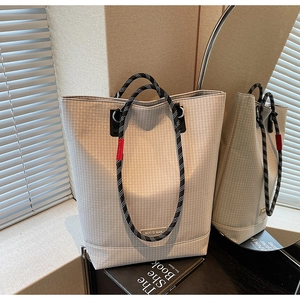 Detail of grey checkered tote bag featuring thick woven rope handles and brand metal logo