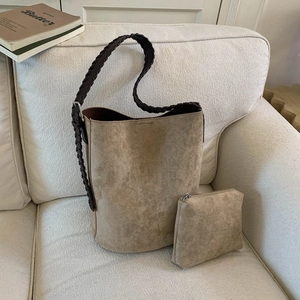 Detail of the khaki suede bucket bag set and inner pouch on a minimalist sofa