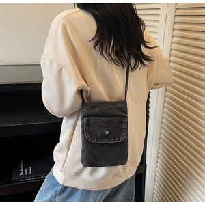 Detail shot of smoke gray denim phone crossbody bag with flap and metal snap button