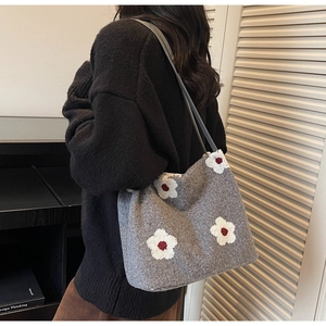 Detail view of grey felt tote bag featuring white floral patterns on a model's shoulder