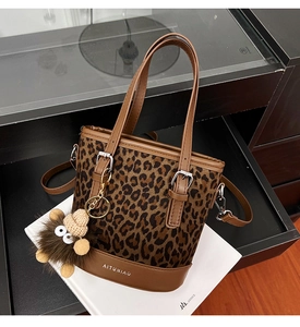 Macro detail of leopard print bucket bag featuring brown faux leather trim and plush charm