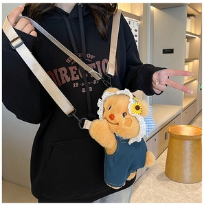 Detail of plush bear bag wearing a blue denim jumpsuit and floral lace hat decoration