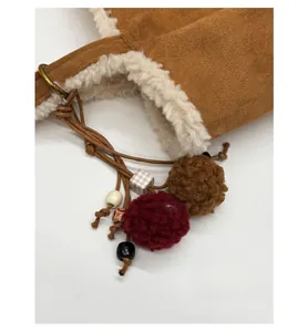 Detail der Wildleder-Einkaufstasche mit weißem Kunstpelzbesatz und Plüschball-Anhänger