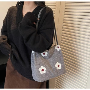 Detail of grey knitted tote bag featuring a white sunflower appliqué and thin black straps