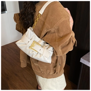 Detail of white pleated shoulder bag with gold buckle and chain strap on a model