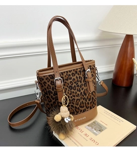 Detail of leopard print bucket bag with brown faux leather trim and plush lamb charm