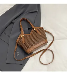 Detail of houndstooth tote bag featuring brown leather trim and golden metal buckle