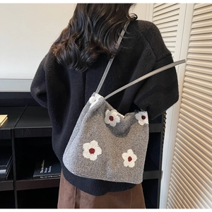 Détail d'un sac bandoulière gris en tricot avec motif floral blanc sur un mannequin