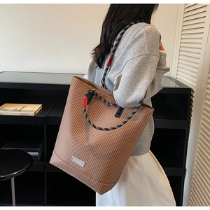 Detailed view of brown striped canvas tote bag with woven rope handle and red accent hooks