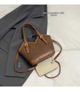 Size reference of a brown houndstooth tote bag compared with a mobile phone